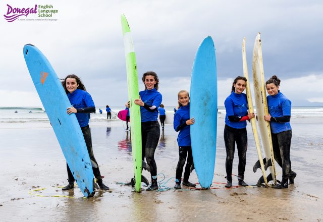 Students carrying surfboards on beach